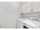White laundry room featuring a washer and dryer set, and white storage cabinets at 11603 Gramercy Park Ave, Bradenton, FL 34211