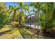 A view of a screened pool enclosure and garden, surrounded by lush greenery and tropical trees, offering privacy and beauty at 11603 Gramercy Park Ave, Bradenton, FL 34211