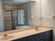 Well-lit bathroom featuring double sinks, dark cabinets, shower, and a decorative stained glass window at 1211 Peridot Lane, Sun City Center, FL 33573