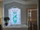 Elegant bathroom featuring custom stained-glass window above garden tub and separate shower at 1211 Peridot Lane, Sun City Center, FL 33573