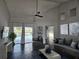 Bright living room with stylish decor, sleek black floors, vaulted ceilings, fan, and sliding doors to the pool at 1211 Peridot Lane, Sun City Center, FL 33573