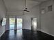Bright living room with sleek black floors, vaulted ceilings, fan, and sliding doors to the pool at 1211 Peridot Lane, Sun City Center, FL 33573
