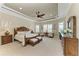 Luxurious main bedroom with tray ceiling, carpet flooring, and a seating area by the windows at 13214 Treviso Dr, Bradenton, FL 34211