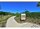 A Pickleball court sign on the side of a paved pathway surrounded by landscaping at 13214 Treviso Dr, Bradenton, FL 34211