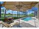 Relaxing screened-in pool with umbrella-covered seating, overlooking lush landscaping and a serene lake at 13214 Treviso Dr, Bradenton, FL 34211