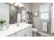 Bathroom featuring a tiled shower, vanity with mirror, and decorative shelves near a bright window at 14540 Gaspar Loop, Port Charlotte, FL 33981
