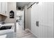 Bright laundry area with white cabinets, a sliding barn door, and an open view to the kitchen at 14540 Gaspar Loop, Port Charlotte, FL 33981