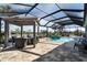 Screened-in pool area featuring a spa, a pergola with seating, and brick flooring, perfect for outdoor living at 14540 Gaspar Loop, Port Charlotte, FL 33981