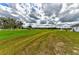 Expansive green field leading to a tranquil pond with a fountain, framed by a classic white fence at 15890 County Road 675, Parrish, FL 34219