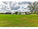 Expansive lawn with metal barn, white fence, and house in the background under cloudy sky at 15890 County Road 675, Parrish, FL 34219