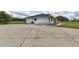 View of the side of the white home with a gray roof, large driveway and two palm trees at 15890 County Road 675, Parrish, FL 34219