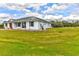 Exterior view of the bright white home, surrounded by expansive green lawn and white fencing at 15890 County Road 675, Parrish, FL 34219