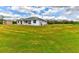Exterior view of the bright white home, surrounded by expansive green lawn and white fencing at 15890 County Road 675, Parrish, FL 34219