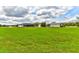 Expansive green field showcasing the home, screened in porch and large lot with a white fence at 15890 County Road 675, Parrish, FL 34219