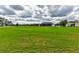 Lush green field with distant view of home and a classic white fence line against a cloudy sky at 15890 County Road 675, Parrish, FL 34219