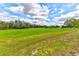 Expansive green field with a classic white fence under a sky filled with fluffy white clouds at 15890 County Road 675, Parrish, FL 34219