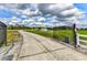Gated driveway leads to the property featuring a serene pond with fountain and lush green surroundings at 15890 County Road 675, Parrish, FL 34219