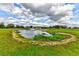 Scenic pond with fountain, surrounded by lush greenery and a white fence, enhances the property's appeal at 15890 County Road 675, Parrish, FL 34219