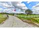 Wide driveway leading to the property with a white fence, green lawn and a pond at 15890 County Road 675, Parrish, FL 34219