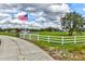 Scenic property view featuring a lush green lawn, pond with fountain, white fence, and an American flag at 15890 County Road 675, Parrish, FL 34219