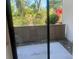 A view of the patio through a sliding glass door showcases the outdoor space and tropical foliage at 1697 Brookhouse Cir # 116, Sarasota, FL 34231