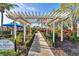 Beautiful landscaped walkway with a pergola and the community pool in the background at 1720 85Th Nw Ct, Bradenton, FL 34209