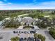 Aerial view of a grand clubhouse with parking and manicured landscaping, surrounded by a golf course at 28 Dominica Dr, Englewood, FL 34223
