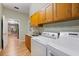 Laundry room featuring wood cabinets, laminate floors, and modern washing and drying units at 28 Dominica Dr, Englewood, FL 34223