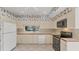 Cozy kitchen with white cabinetry, white appliances, a view of the golf course, and floral wallpaper at 3864 Chatsworth Greene Ct # 10, Sarasota, FL 34235