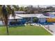 Charming home featuring a metal roof, vibrant turquoise front door, nicely manicured lawn, and well-kept landscaping at 4210 Pandora Rd, Venice, FL 34293
