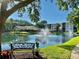 Scenic view of a pond with a fountain, lush greenery, a bench, and surrounding community buildings at 435 30Th W Ave # D303, Bradenton, FL 34205