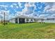 Wide view of expansive green lawn and rear exterior of the home with a screened porch at 44325 Saddlewood Ct, Punta Gorda, FL 33982