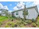 A green lawn with new landscaping features a peaceful view of a white home with a screened lanai at 44325 Saddlewood Ct, Punta Gorda, FL 33982