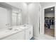 Modern bathroom with double sinks, white cabinetry, a glass-enclosed shower, and walk-in closet at 44325 Saddlewood Ct, Punta Gorda, FL 33982