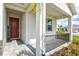 Inviting covered porch featuring a welcoming red front door and stylish gray-toned pavers at 44325 Saddlewood Ct, Punta Gorda, FL 33982