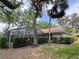 Home exterior featuring a screened lanai, mature trees, and well-maintained landscaping offering privacy and curb appeal at 5714 Garden Lakes Fern, Bradenton, FL 34203