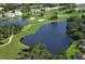 Scenic aerial view of a golf course featuring a pond and manicured green with surrounding trees at 6114 Misty Oaks St, Sarasota, FL 34243