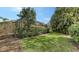 Expansive backyard with lush greenery, privacy hedges, a screened lanai, and mature trees at 6114 Misty Oaks St, Sarasota, FL 34243