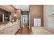 Bathroom featuring double sinks, granite counters, white cabinets, and a walk-in closet at 6114 Misty Oaks St, Sarasota, FL 34243