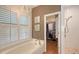 Bathroom features tub, window shutters and an adjacent walk-in shower and walk-in closet at 6114 Misty Oaks St, Sarasota, FL 34243