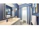 Stylish blue bathroom with striking striped curtains, ample vanity counter space, and a decorative mirror at 6114 Misty Oaks St, Sarasota, FL 34243