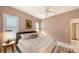 Bedroom with light pink walls and a ceiling fan featuring plantation shutters and adjacent bathroom at 6114 Misty Oaks St, Sarasota, FL 34243
