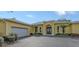 Single Gathering home featuring a two-car garage, arched entrance, and manicured landscaping at 6114 Misty Oaks St, Sarasota, FL 34243