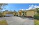 Charming yellow home featuring an arched entryway, well-manicured landscaping, and an attached two-car garage at 6114 Misty Oaks St, Sarasota, FL 34243