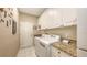 Well-equipped laundry room with white cabinets, granite countertops, and modern washer and dryer units at 6114 Misty Oaks St, Sarasota, FL 34243