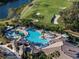 Aerial view showcases a resort-style pool area with palm trees, lounge chairs, and a golf course in a vibrant community at 6560 Willowshire Way, Bradenton, FL 34212