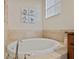 Bright bathroom with a large soaking tub and tiled surround under a window at 6560 Willowshire Way, Bradenton, FL 34212