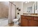 Bathroom with a shower-tub combo with a shower curtain and a vanity with granite countertop at 6560 Willowshire Way, Bradenton, FL 34212