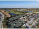 Aerial view showcases multiple tennis courts, pool, and community with lake and golf course backdrop at 6560 Willowshire Way, Bradenton, FL 34212