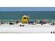 Bright, sunny beach scene featuring lifeguard station, umbrellas, and various beach goers enjoying the sun at 732 Siesta Dr, Sarasota, FL 34242